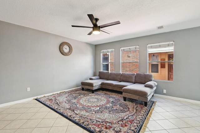 living area with light tile patterned floors, visible vents, a textured ceiling, and a ceiling fan