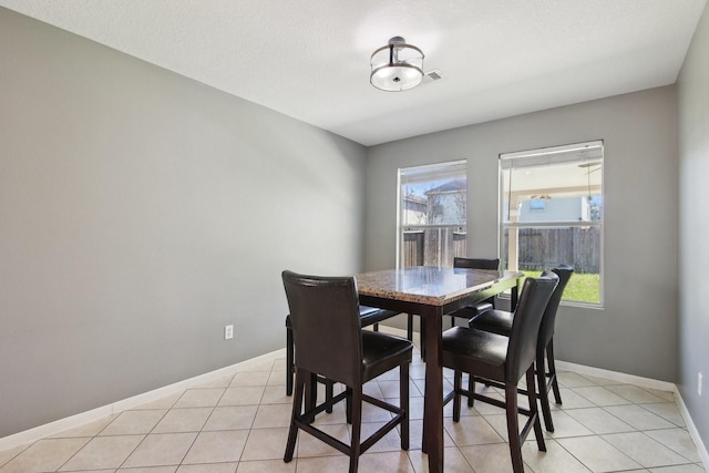 dining area with light tile patterned floors, a healthy amount of sunlight, and baseboards