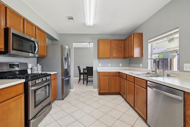 kitchen featuring brown cabinetry, visible vents, a sink, light countertops, and appliances with stainless steel finishes