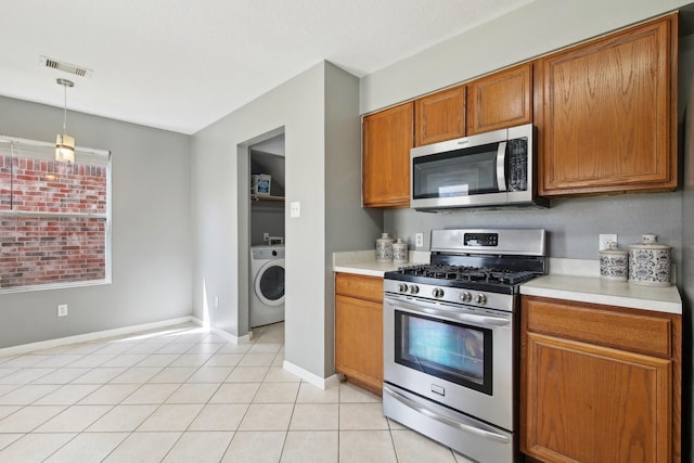 kitchen featuring visible vents, light countertops, brown cabinets, appliances with stainless steel finishes, and washer / clothes dryer