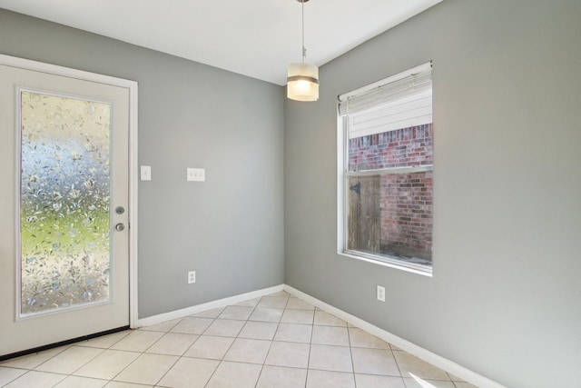 unfurnished room with light tile patterned floors, a healthy amount of sunlight, and baseboards