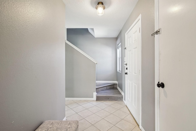 foyer featuring stairway, light tile patterned flooring, and baseboards