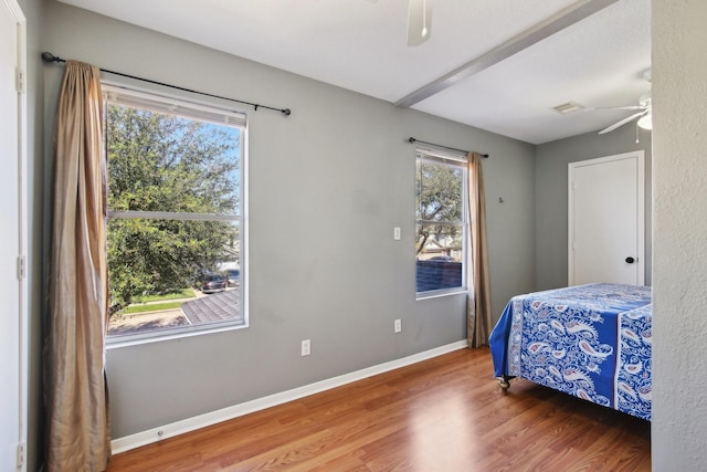 bedroom featuring visible vents, a ceiling fan, baseboards, and wood finished floors