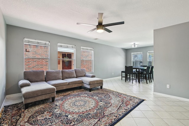 living room with a wealth of natural light, a textured ceiling, ceiling fan, and light tile patterned flooring