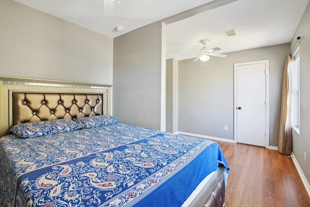 bedroom featuring visible vents, ceiling fan, baseboards, and wood finished floors