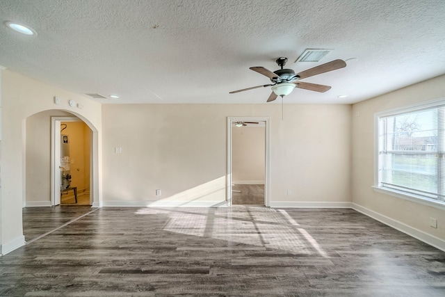 spare room with visible vents, arched walkways, baseboards, and wood finished floors