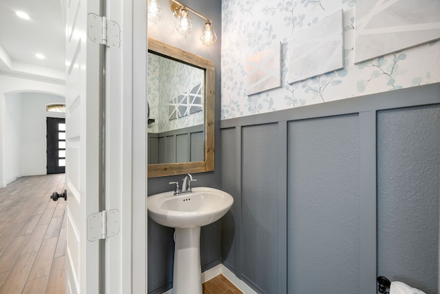 bathroom featuring wainscoting, wallpapered walls, and wood tiled floor