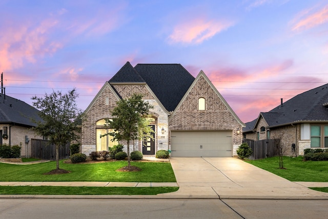 french country style house with brick siding, concrete driveway, and a lawn