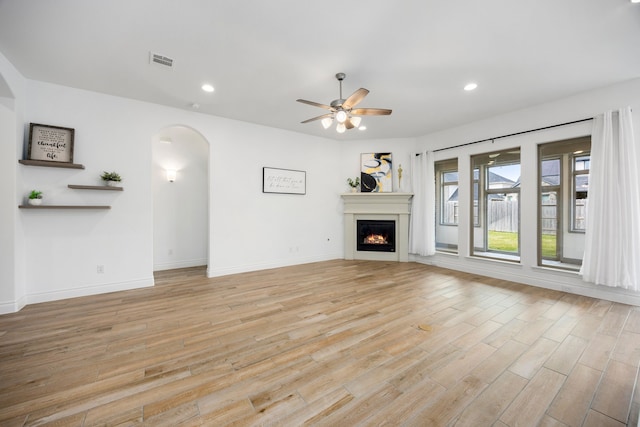 unfurnished living room with recessed lighting, visible vents, light wood-style floors, and a warm lit fireplace