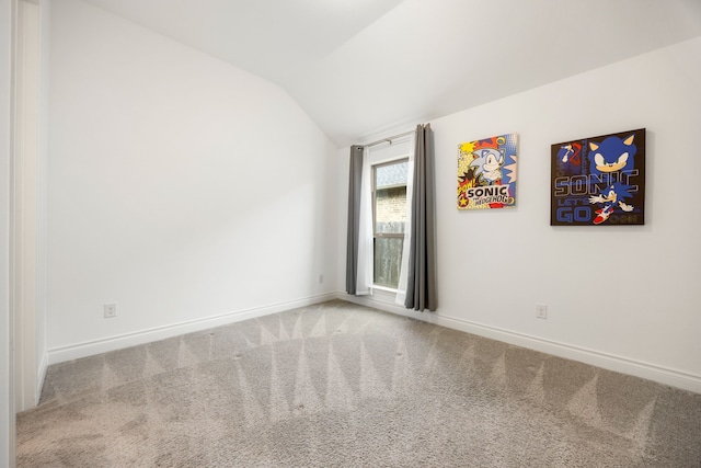 spare room featuring baseboards, carpet flooring, and vaulted ceiling