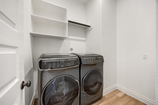 laundry area with washer and dryer, laundry area, wood finished floors, and baseboards