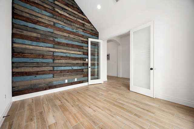 unfurnished room featuring wood finished floors, recessed lighting, french doors, arched walkways, and lofted ceiling