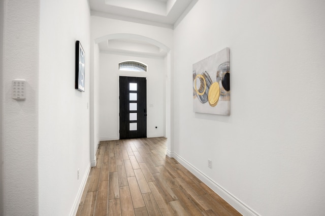 foyer with arched walkways, baseboards, and wood finished floors