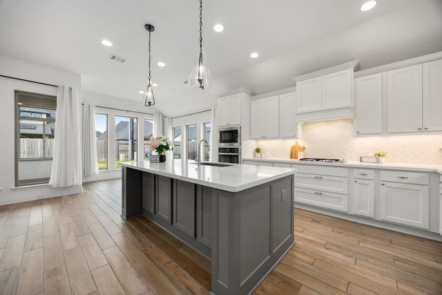 kitchen featuring visible vents, light wood-type flooring, stainless steel appliances, light countertops, and tasteful backsplash