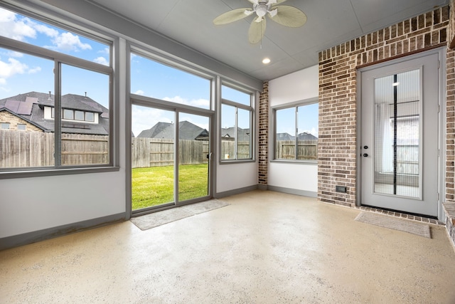 unfurnished sunroom with a residential view, a wealth of natural light, and ceiling fan