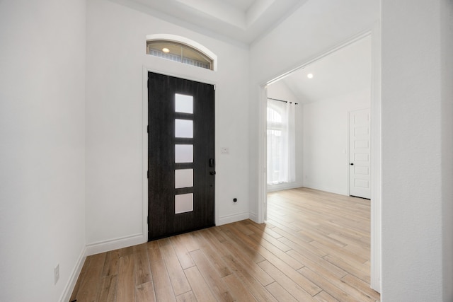 foyer entrance with baseboards, lofted ceiling, and light wood-style flooring