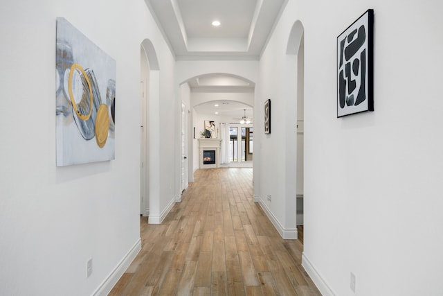 hall with recessed lighting, light wood-type flooring, baseboards, and arched walkways