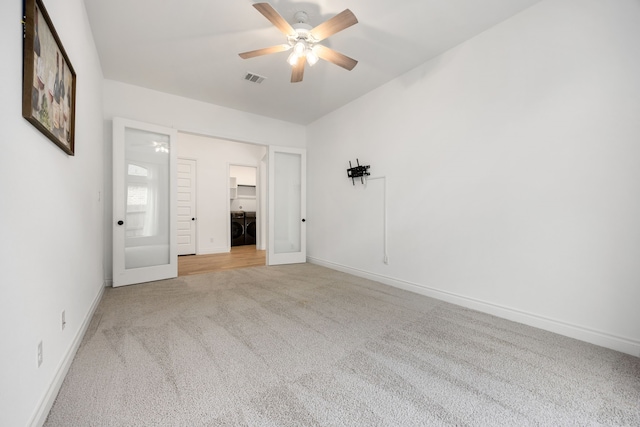 unfurnished room with visible vents, washer and clothes dryer, baseboards, light colored carpet, and ceiling fan