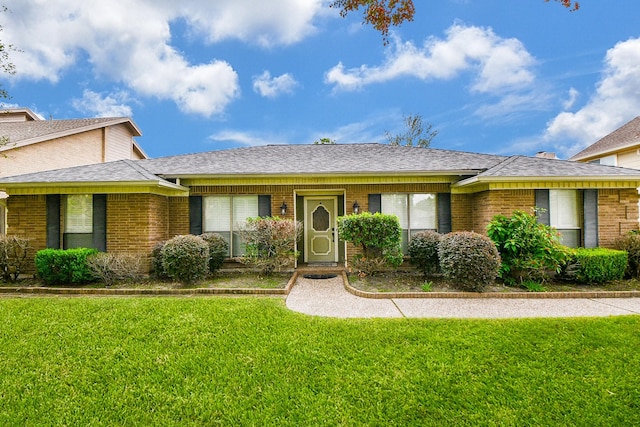 ranch-style home with brick siding, a front yard, and a shingled roof