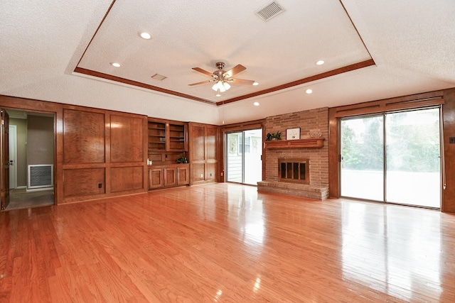 unfurnished living room with visible vents, light wood-style flooring, and a tray ceiling