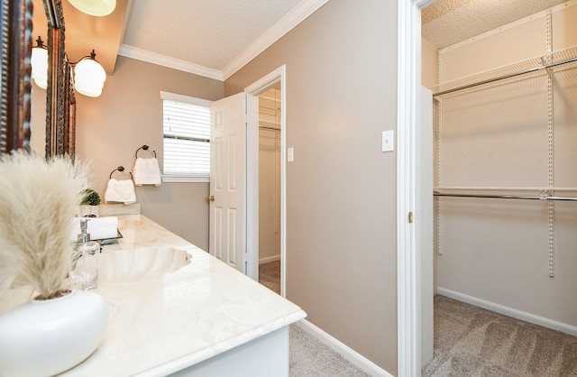 bathroom with vanity, a textured ceiling, baseboards, and ornamental molding