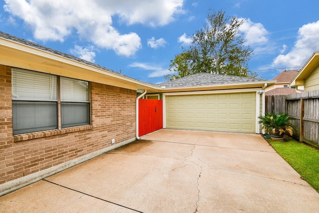 view of front of house with brick siding, driveway, a garage, and fence