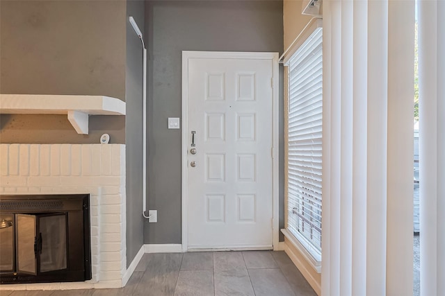 foyer featuring a fireplace, baseboards, and a healthy amount of sunlight