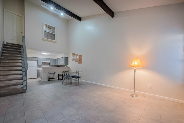 interior space with beam ceiling, stairway, baseboards, and a towering ceiling