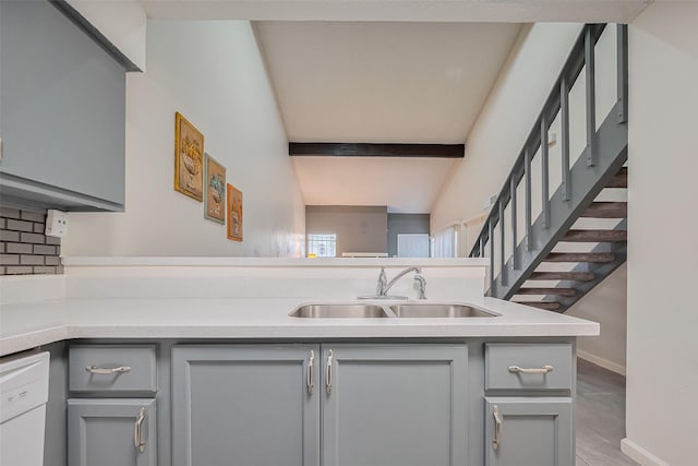 kitchen with light countertops, vaulted ceiling with beams, a sink, baseboards, and gray cabinetry