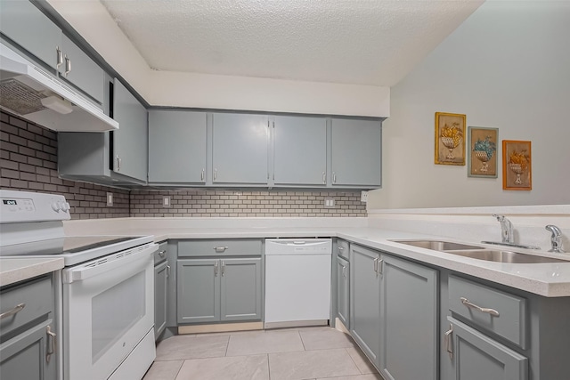 kitchen featuring under cabinet range hood, gray cabinets, light tile patterned flooring, white appliances, and a sink