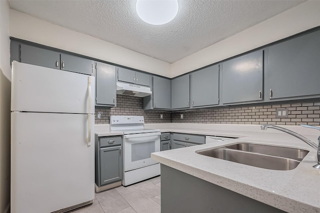 kitchen featuring white appliances, gray cabinets, a sink, light countertops, and under cabinet range hood