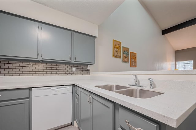 kitchen featuring tasteful backsplash, dishwasher, lofted ceiling with beams, gray cabinets, and a sink