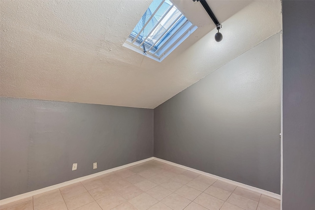 bonus room with baseboards, vaulted ceiling with skylight, and a textured ceiling