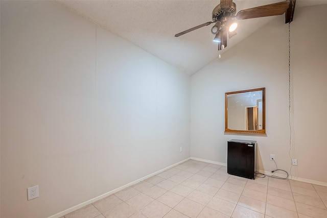 empty room with light tile patterned flooring, baseboards, a ceiling fan, and vaulted ceiling