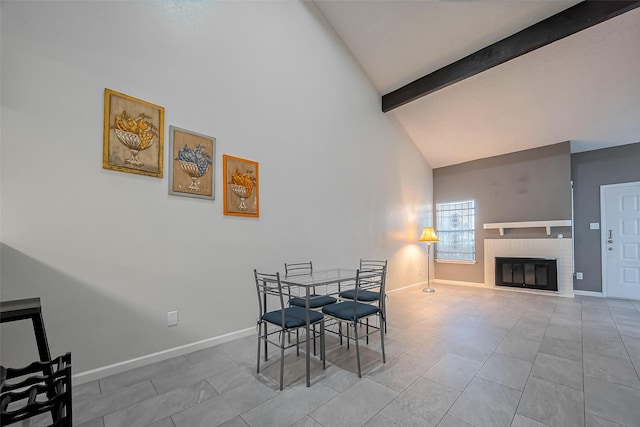 dining room featuring baseboards, beam ceiling, high vaulted ceiling, and a brick fireplace