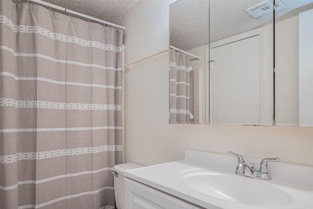 bathroom featuring visible vents, curtained shower, toilet, vanity, and a textured ceiling