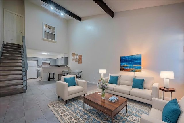 living area with baseboards, a towering ceiling, beamed ceiling, tile patterned flooring, and stairway