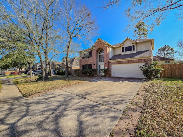 traditional-style house with driveway, fence, a shingled roof, a garage, and brick siding