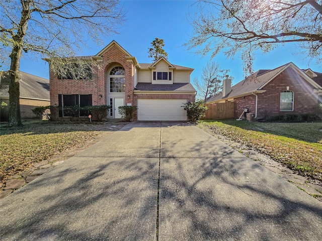 traditional-style home featuring driveway, fence, a front yard, an attached garage, and brick siding