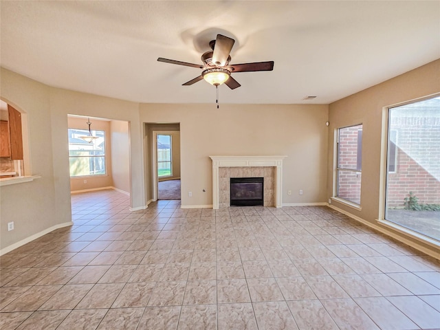 unfurnished living room with a ceiling fan, visible vents, baseboards, light tile patterned flooring, and a tiled fireplace