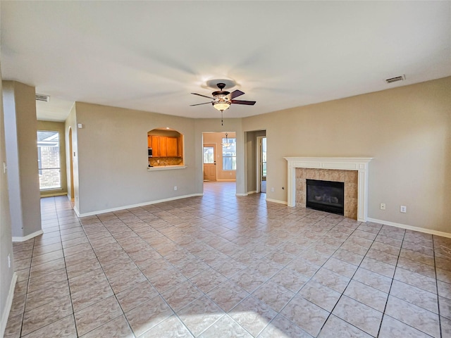 unfurnished living room with visible vents, baseboards, a tiled fireplace, light tile patterned floors, and a ceiling fan