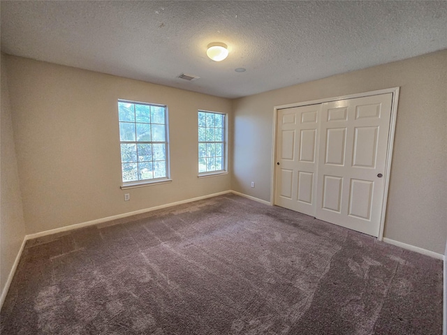 unfurnished bedroom featuring a closet, baseboards, carpet, and a textured ceiling