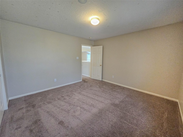 carpeted empty room featuring baseboards and a textured ceiling