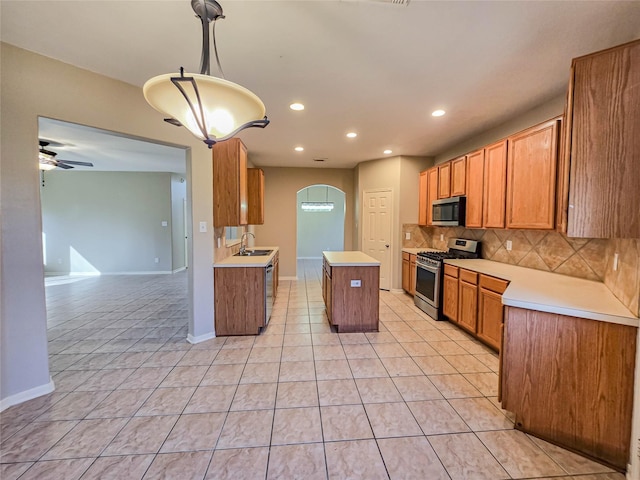 kitchen featuring light tile patterned flooring, arched walkways, decorative backsplash, light countertops, and appliances with stainless steel finishes