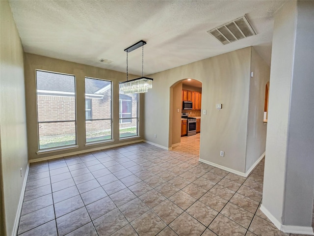 unfurnished dining area featuring light tile patterned floors, arched walkways, visible vents, and a textured ceiling