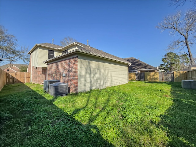 rear view of property with a yard, a fenced backyard, brick siding, and central AC