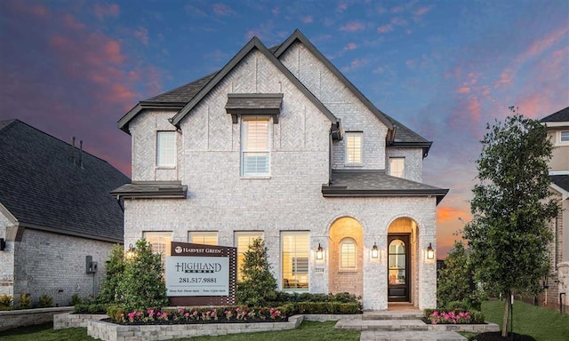 french country home featuring brick siding