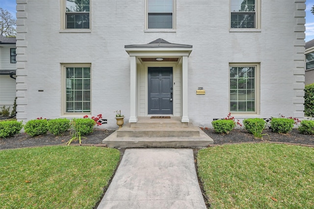 property entrance featuring a yard and brick siding