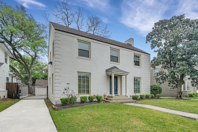 colonial-style house with a front lawn, a gate, and a chimney