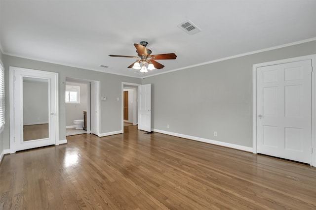 interior space with visible vents, baseboards, wood finished floors, and crown molding